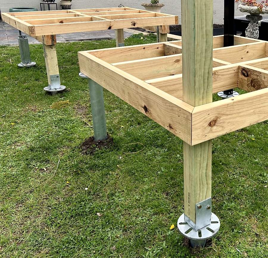 Timber pergola post carried through a deck subframe and bolted into a bracket on a screw pile flange