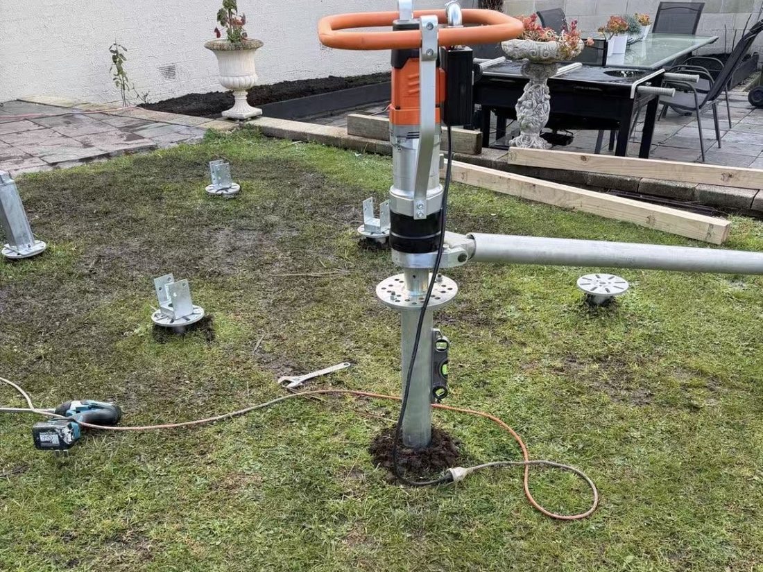 Several galvanised screw piles driven to level with post brackets fitted, showing minimal ground disturbance